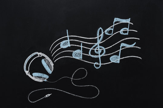 headphones with wire and musical notes drawn on black chalkboard