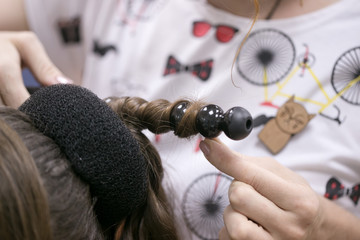 a hairdresser does a hairstyle for a girl in a hairdresser's 