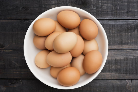 Fresh hen egg in white bowl on Black color wood table