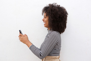 Side of cheerful african american woman holding smart phone