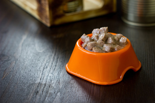 Canned pet food in a orange plastic bowl.