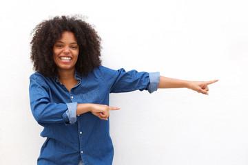 Happy young woman smiling and pointing against white background