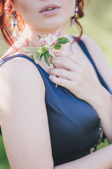 Young beautiful woman with red hair in a blue dress posing in a blooming garden