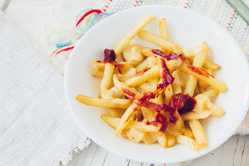 Poutine fries with tomato sauce and cheese on white table.