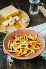 Poutine fries on black surface. Canadian dish with potatoes, cheese and sauce.