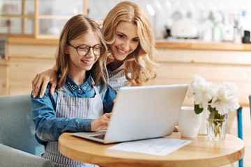 Caring mother helping her daughter with home assignment