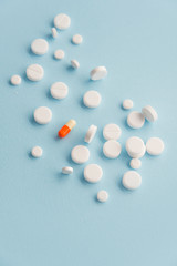 Top view of one colorful pill surrounded by white pills