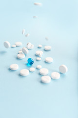 Fallen white tablets with one blue capsule isolated