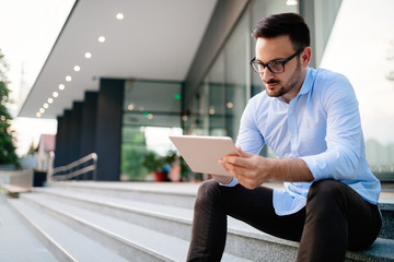 Portrait of businessman in glasses holding tablet
