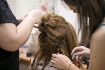a hairdresser does a hairstyle for a girl in a hairdresser's 