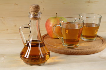 Apple cider and fruit on wooden background.