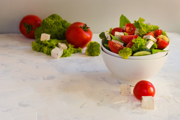 Lettuce leaves, cherry tomatoes, cucumber, broccoli and tofu salad on white background.