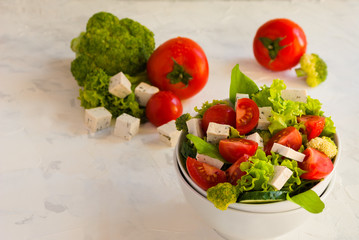 Lettuce leaves, cherry tomatoes, cucumber, broccoli and tofu salad on white background.