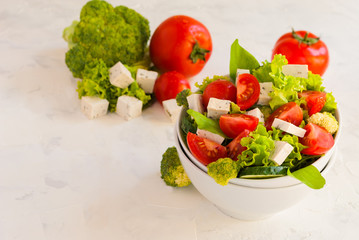 Lettuce leaves, cherry tomatoes, cucumber, broccoli and tofu salad on white background.