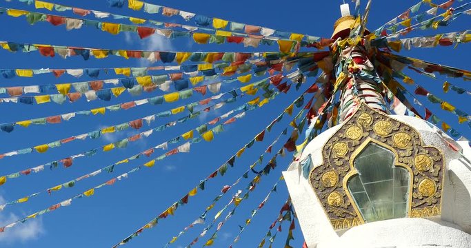 4k buddhist white stupa & flying prayer flags with blue sky background,shangrila yunnan,china.