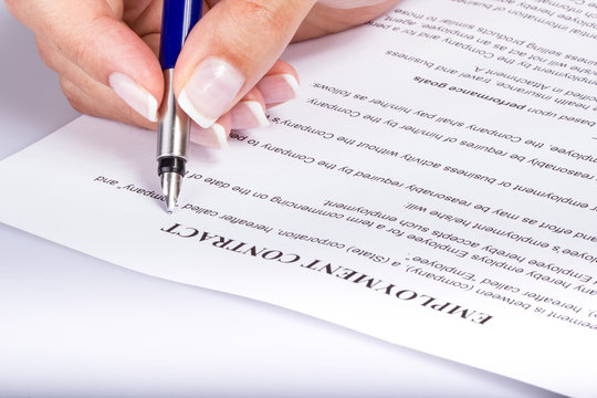 Employee signing the employment contract, closeup of a female hand holding a fountain pen above the legal document