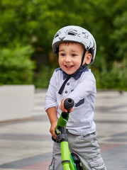 Fototapeta na wymiar Child boy in white helmet riding on his first bike with a helmet. Bike without pedals.