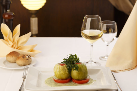Stuffed zuchini arranged on a plate, Wineglass in the background, Traditional dish in elegant setting, Selective focus with soft light
