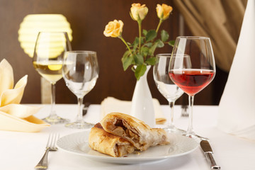 Apple pie slice arranged on a plate, Wineglass in background, Traditional dessert in elegant setting, Selective focus with soft light