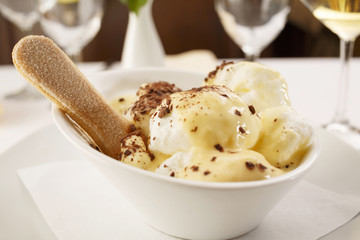 Egg white with vanilla mousse arranged on a plate, Wineglass in background, Traditional dessert in elegant setting, Selective focus with soft light