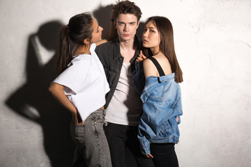 Concentrated young hipster man standing with friends women