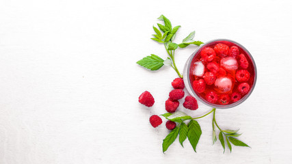 Cocktail of fresh raspberries with ice, on a wooden background. Top view. Free space.