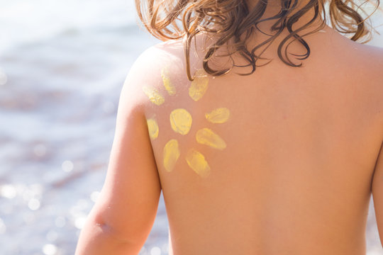 Kleines Kind am Meer mit Sonnencreme auf der Schulter