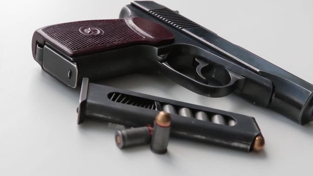 A military pistol on a white window sill, sunlight from a window