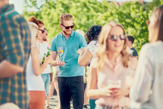 Group of best friends chatting and drinking while standing at outdoor party