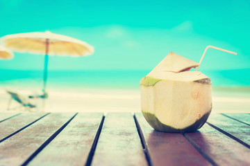 Fototapeta na wymiar Coconut juice on wood table in blurred beach background