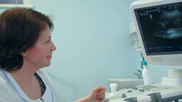 Smiling female doctor explaining ultrasound results looking at the screen