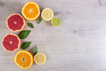 Fototapeta na wymiar Juicy citrus fruits cut background mint leaf. Oranges, lemons, limes, grapefruit, mint leaves on a bright wooden background