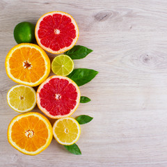 Juicy citrus fruits cut background mint leaf. Oranges, lemons, limes, grapefruit, mint leaves on a bright wooden background