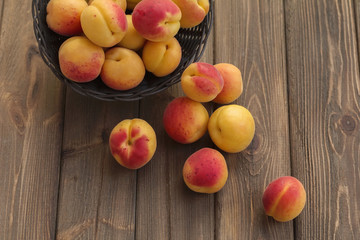 Ripe apricots in basket on wooden table, top view