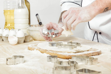 Man chef in uniform makes cookies with baking forms