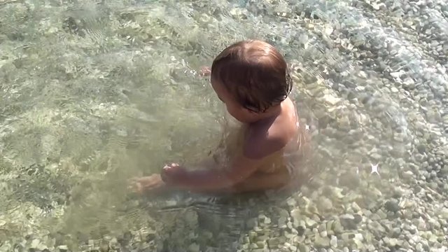 Adorable baby splashes in the sea water