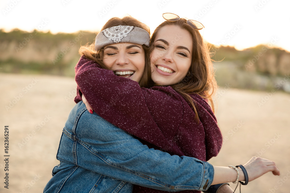 Poster Two smiling feamale friends hugging each other