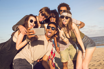 Cheerful multiethnic friends taking selfie at beach on sunny day