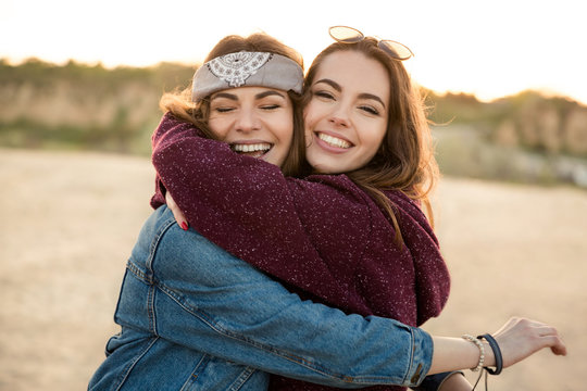 Two smiling feamale friends hugging each other