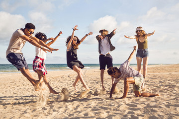 Happy young people jumping on the beach