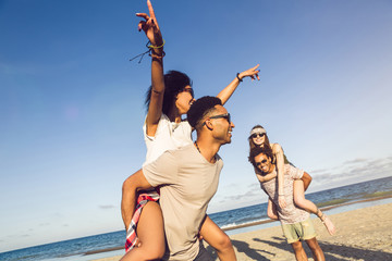 Two young men giving their girlfriends piggyback rides