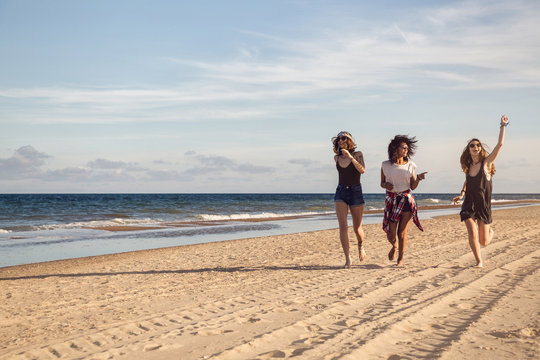 Group of three beautiful young women walking on the beach
