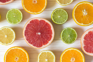 Slices of lemon, orange, lime and grapefruit on white wooden table. Pattern of food.