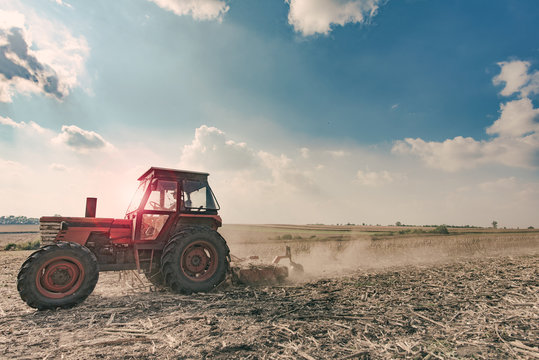 Farmer in tractor preparing land, agricultural works at farmlands.