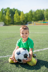 Positive boy child playing football on the field.