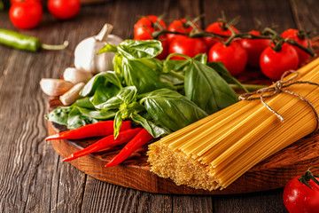Products for cooking - pasta, tomatoes, garlic, pepper, and basil.