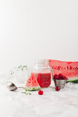 Glass jar cup with refreshing watermelon and strawberry lemonade with lime juice, ginger and honey on marble table and white background. Summertime beverage concept. Copy space