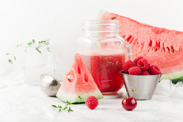 Glass jar cup with refreshing watermelon and strawberry lemonade with lime juice, ginger and honey on marble table and white background. Summertime beverage concept. Copy space