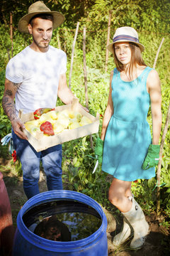 Young couple washing bell pepper in barrel