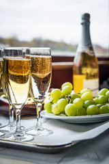 Champagne in glasses, bottle and grapes on the table